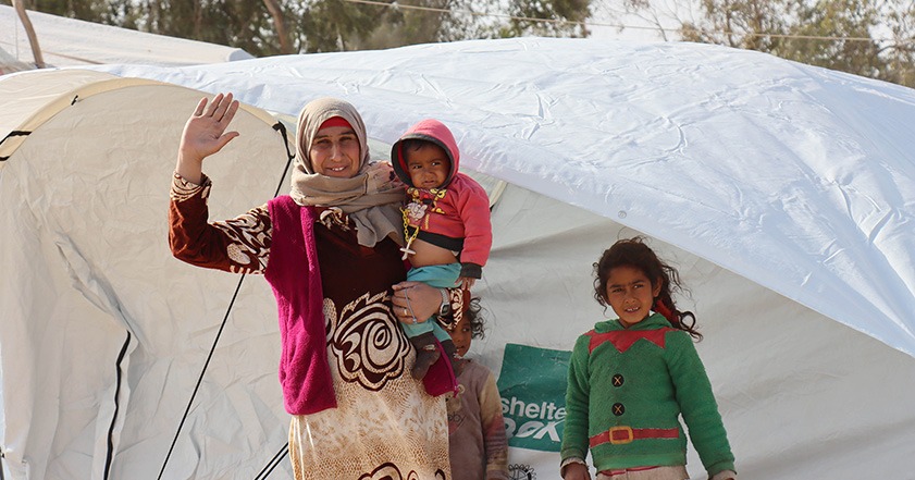 Eine Frau und drei Kinder in warmer Kleidung vor einem Zelt in Syrien