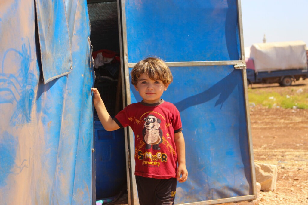 Ein Junge steht vor einem Zelt in Syrien