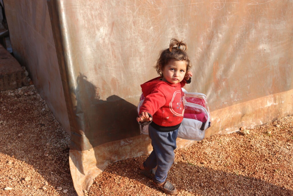 Ein junges Kind in Winterkleidung trägt weitere Kleidungsstücke in Syrien