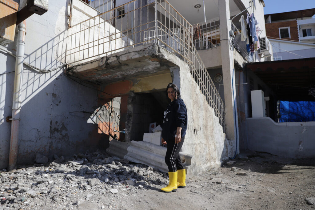 Frau steht neben einer beschädigten Treppe vor einem Haus in der Türkei