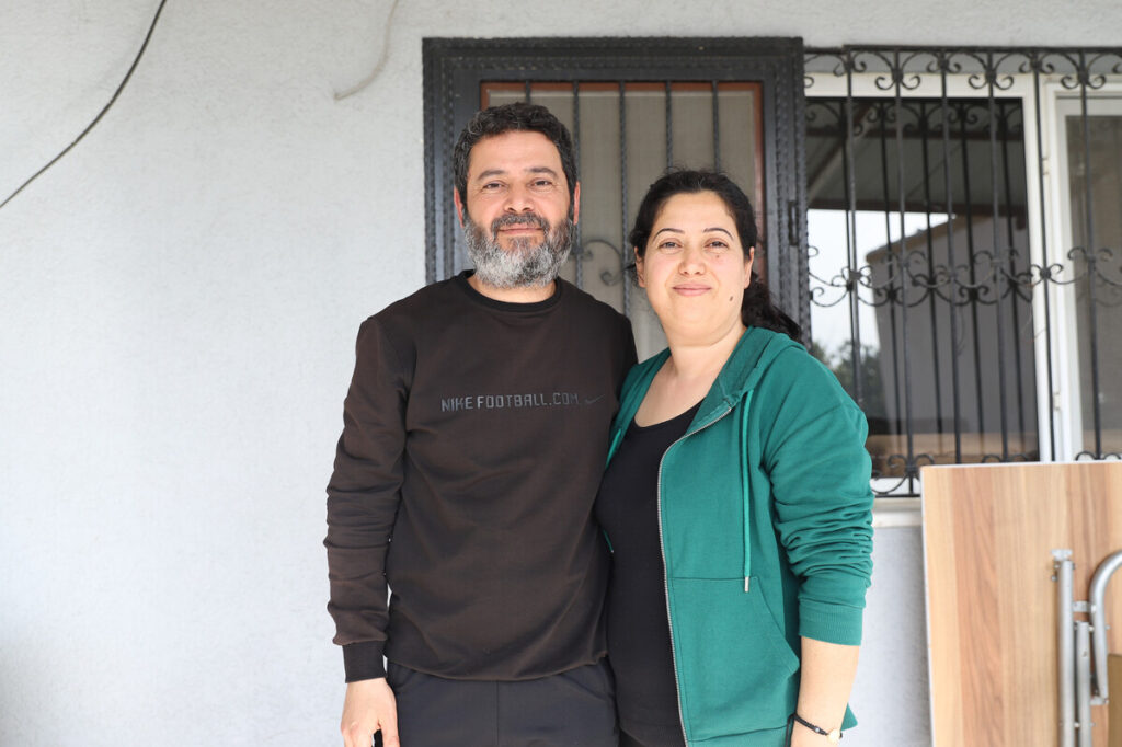 Ein Mann und eine Frau stehen vor einem beschädigten Haus in der Türkei