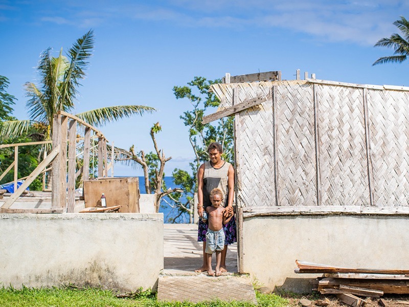 Frau und Kind stehen in ihrem zerstörten Haus, nachdem der Zyklon Harold Vanuatu heimgesucht hat.