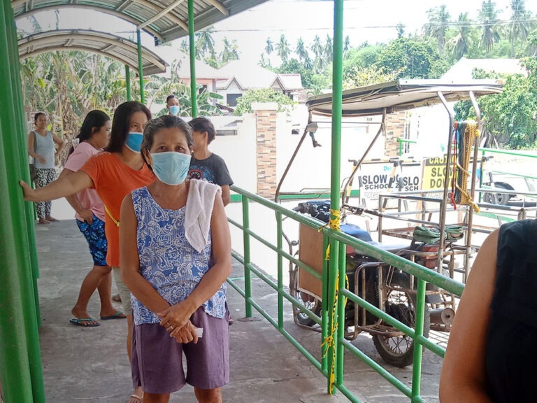 Menschen, die während der Coronavirus-Pandemie in den Philippinen auf Hilfsgüter warten, halten Abstand zueinander und tragen Gesichtsmasken.
