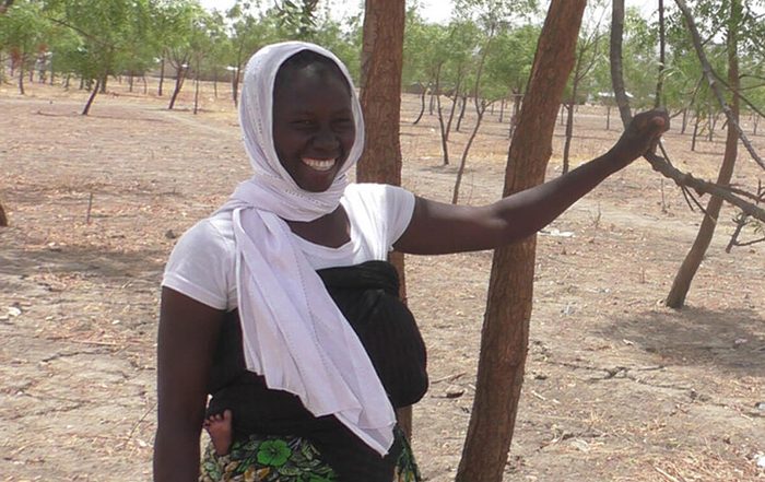 Woman wearing white head scarf next to a tree in Cameroon