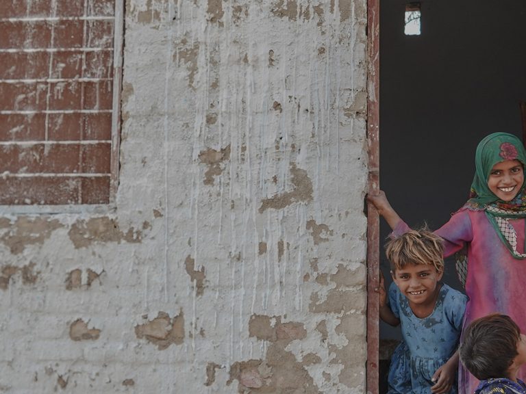 Drei Kinder vor dem Eingang einer Notunterkunft in Pakistan