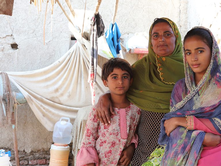 Frau und zwei Kinder sitzen in einer Notunterkunft in Pakistan