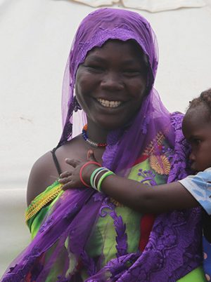 Woman holding a young child in front of a tent in Chad