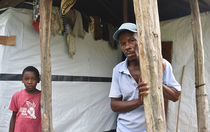Man and child standing outside home in Haiti