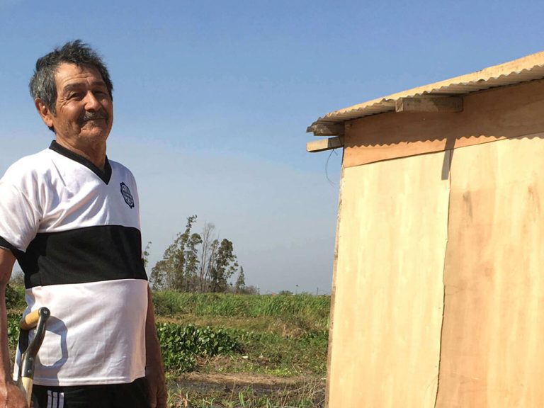 Mann mit Schaufel vor seinem Haus in Paraguay