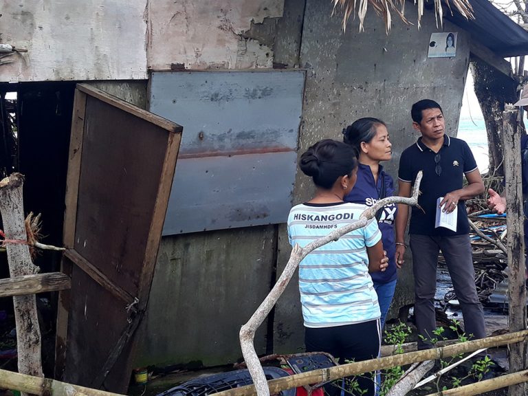 Menschen neben einem beschädigten Gebäude auf den Philippinen