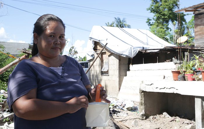 Woman holding a solar light outside a repaired building in the Philippines