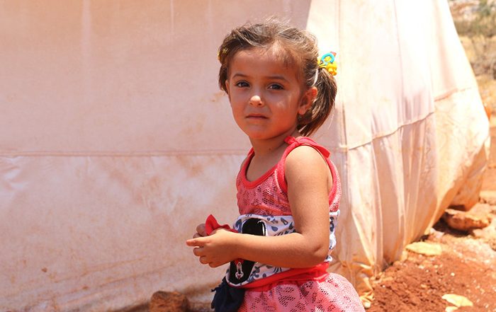 Little girl next to tent in Syria