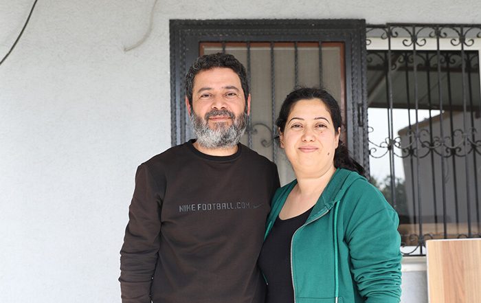 Man and woman standing in front of a damaged building in Turkey