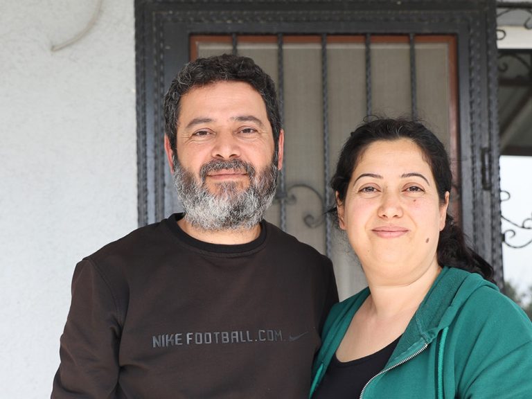 Man and woman standing in front of a damaged building in Turkey