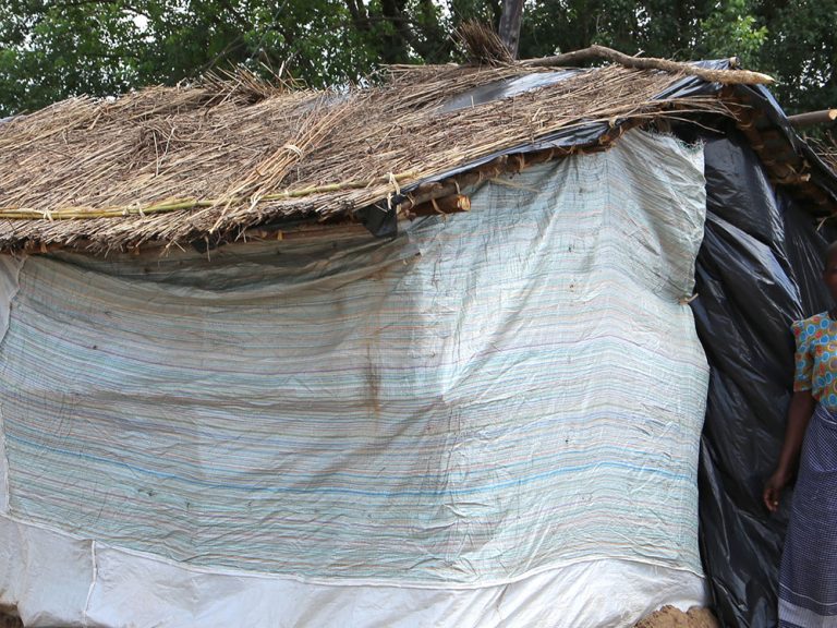 Menschen stehen neben einem reparierten Haus in Malawi