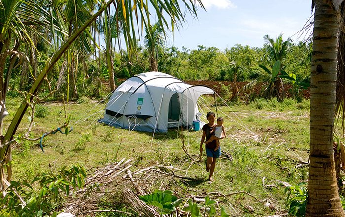 Woman carrying a child in front of a tent in the Philippines