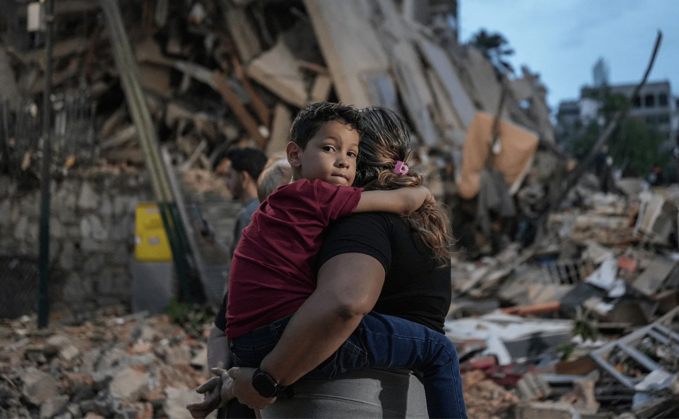 People walk past a collapsed building following an earthquake in Caracas on June 25, 2026. Powerful twin earthquakes have killed 32 people and injured more than 700, the nation's interim president said on June 25, after the massive shocks collapsed entire buildings and sent people running in panic.